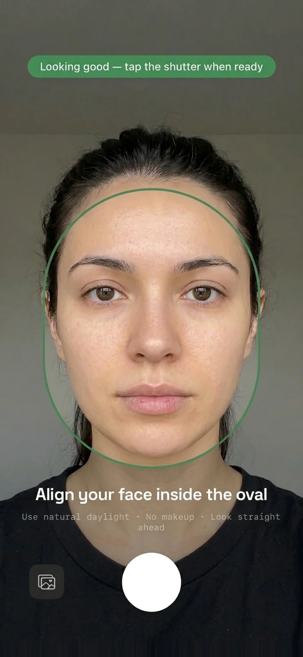 The camera screen, face centred in the oval guide which has turned green, with the live tip reading 'Looking good — tap the shutter when ready'.